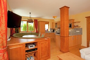 A compact kitchen with wooden cabinets, a built-in microwave, and a window with curtains. - Chalet in Saalbach Near Ski Lift (Saalbach-Hinterglemm)