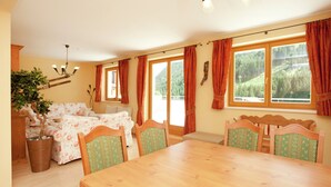 A dining area with a wooden table and chairs, a sofa, and a potted plant. - Chalet in Saalbach Near Ski Lift (Saalbach-Hinterglemm)