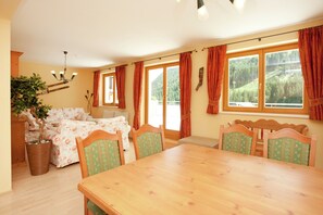 A dining area with a wooden table and chairs, a sofa, and a potted plant. - Chalet in Saalbach Near Ski Lift (Saalbach-Hinterglemm)