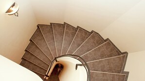 A spiral staircase with a handrail and a light fixture on the wall. - Chalet in Saalbach Near Ski Lift (Saalbach-Hinterglemm)