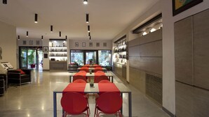 A modern restaurant with long tables and red chairs, a bar area with shelves of bottles, and a view of greenery outside. - Charming Villa in Maida With Pool & Garden (San Pietro a Maida)