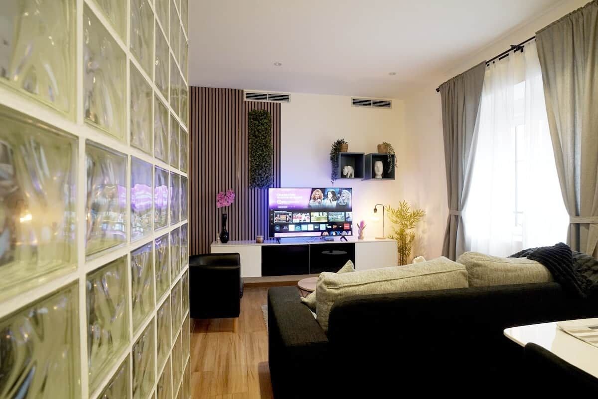 Ein modernes Wohnzimmer mit großem Flachbildfernseher, einer Couch, einem Couchtisch und einer Glastruhe.