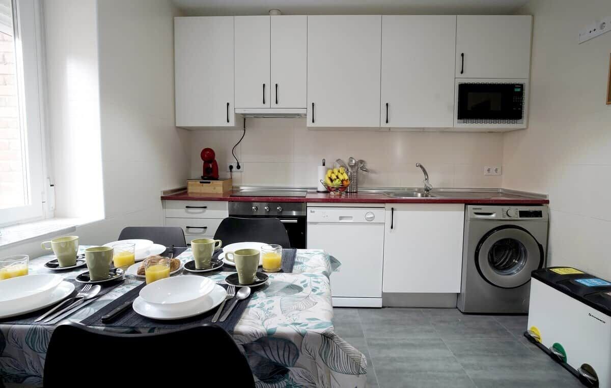 A compact kitchen with white cabinets, a microwave, a sink, and a washing machine.