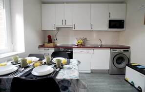 A compact kitchen with white cabinets, a microwave, a sink, and a washing machine. - Murallas Home (Ávila)