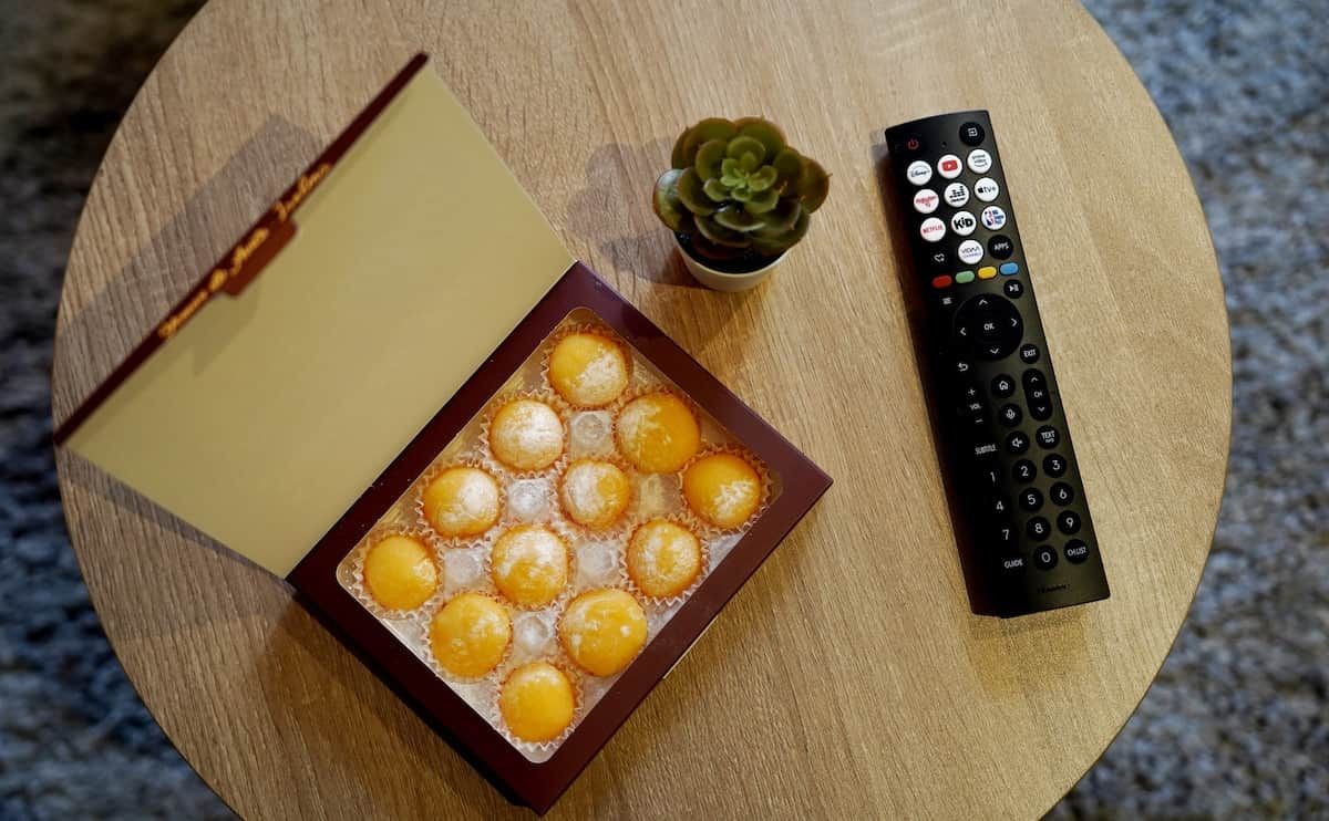 En fjernbetjening, en bog og en bakke med snacks på et rundt bord.