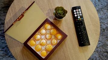 En fjernbetjening, en bog og en bakke med snacks på et rundt bord.