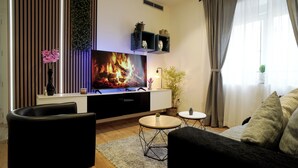 A modern living room with a flat-screen TV, black sofas, a round coffee table, and a small side table. - Just 10 minutes from the City Walls! An ideal home for friends and families. (Ávila)