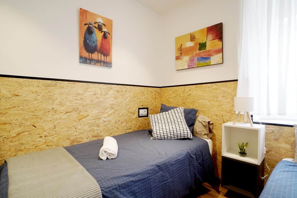 Une chambre avec deux lits, une tête de lit en bois, une table de chevet avec une lampe et deux œuvres d’art murales.