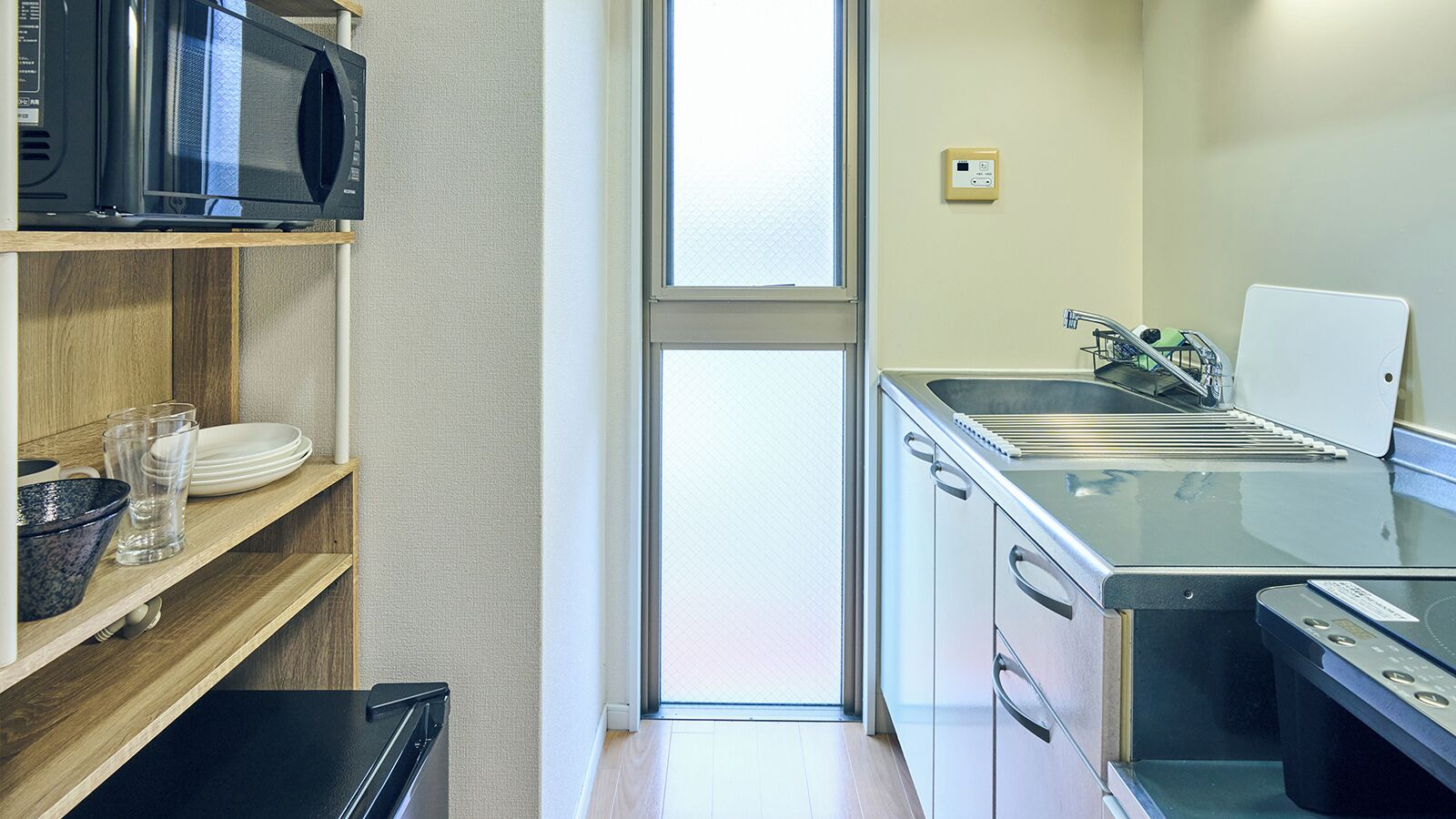 A compact kitchen with a microwave, oven, sink, and a window.