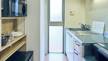 A compact kitchen with a microwave, oven, sink, and a window.