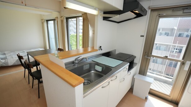 A compact kitchen with a sink, a small countertop, and a window with curtains. - Sakurakan (Kagoshima)