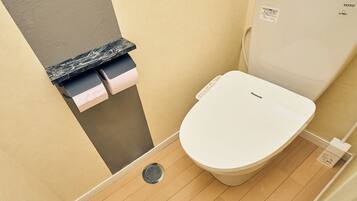 A toilet with a white seat and lid, a black marble countertop, and a roll of toilet paper dispenser.