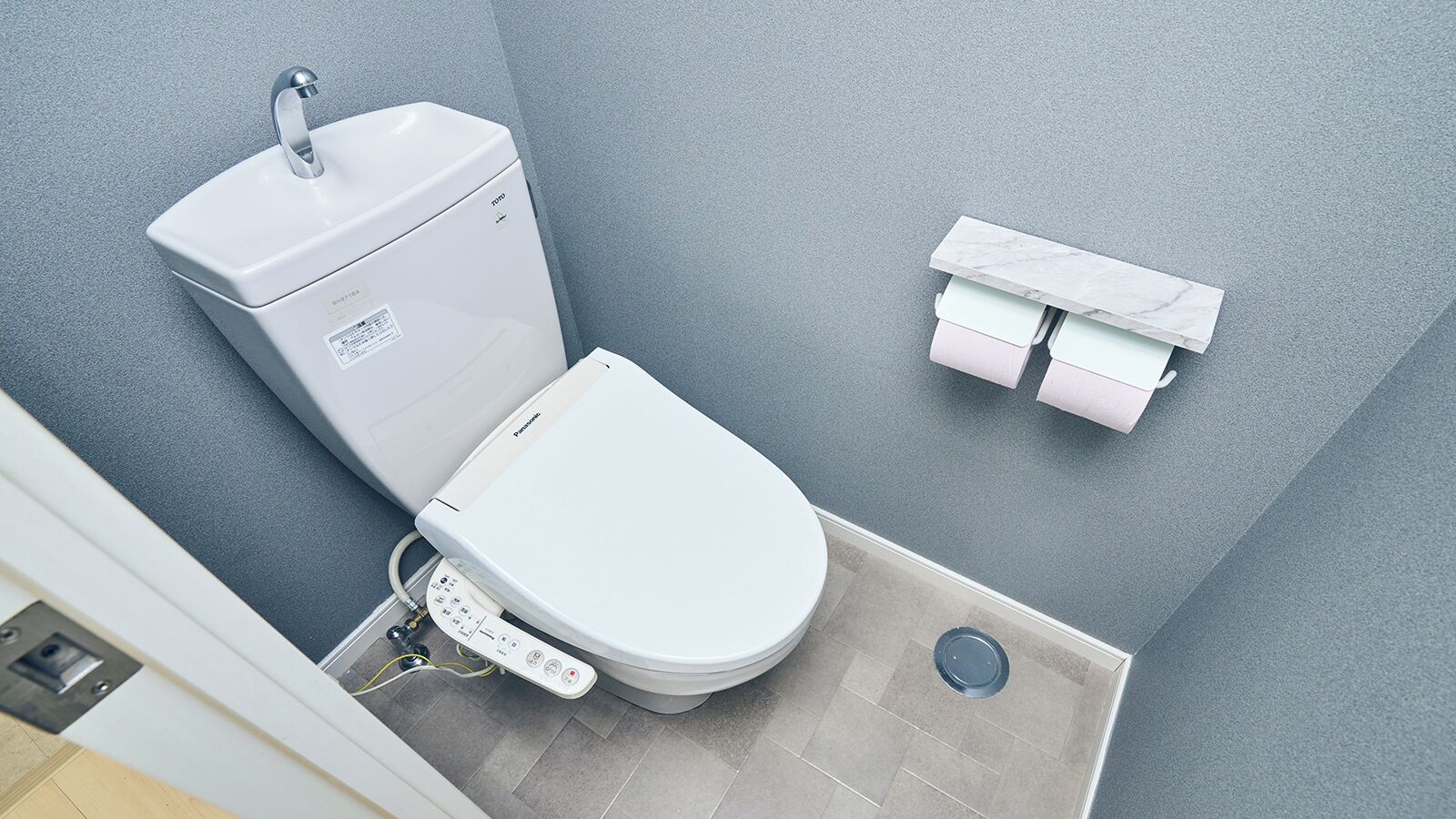 A modern bathroom with a toilet, a bidet, and a marble shelf.