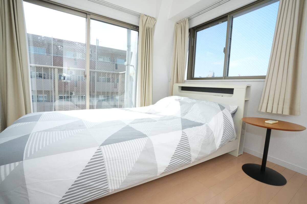 Un dormitorio con cama, una mesita redonda y una ventana con cortinas.