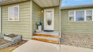 Une maison avec un porche à l’avant, une porte dotée d’un panneau en verre et un petit jardin avec des marches menant à la porte.