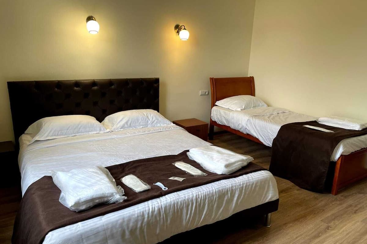 Ett hotellrum med två sängar, en sänggavel i trä och två väggmonterade lampor.