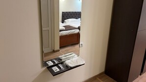 A bedroom with a bed, a mirror, and a shelf with toiletries. - Nana Grand Hotel (Yerevan)