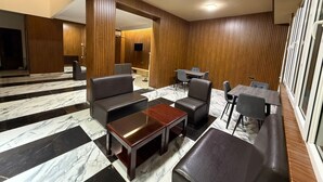 A modern lobby with a marble floor, leather seating, a wooden reception desk, and a TV mounted on the wall. - Nana Grand Hotel (Yerevan)