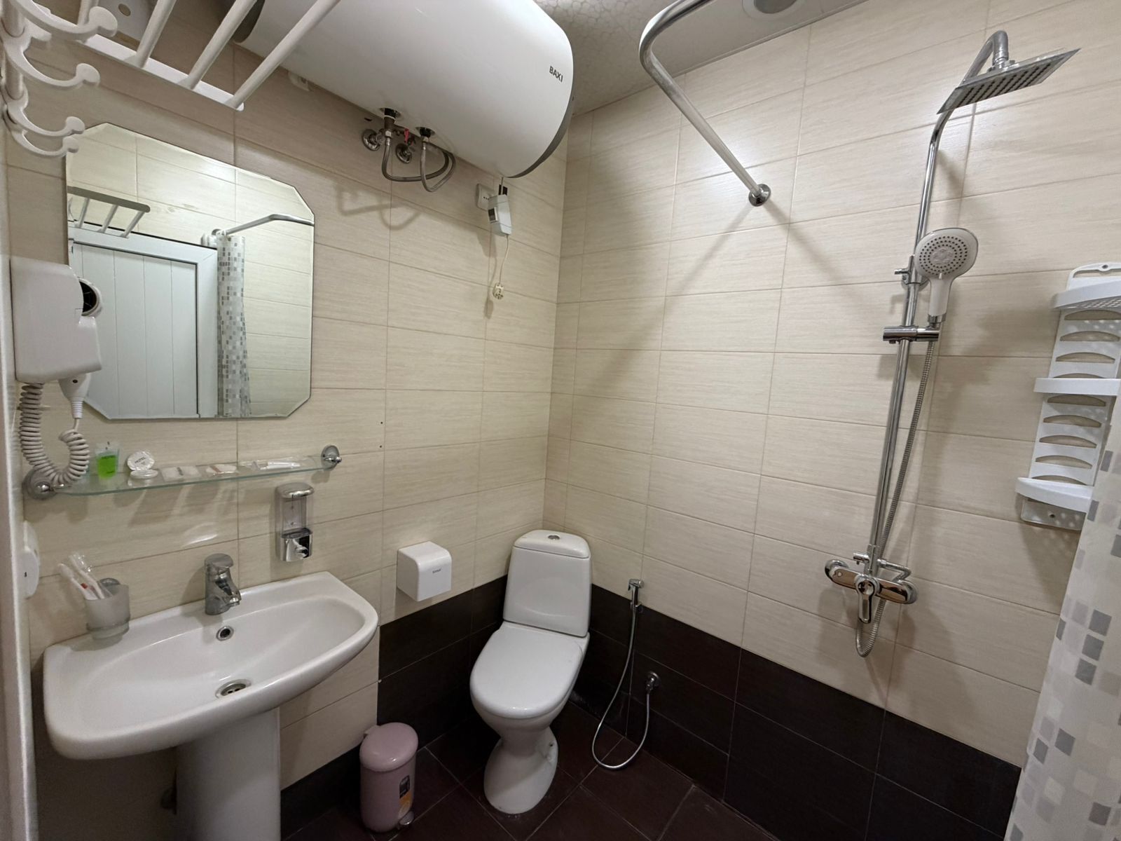 Une salle de bain équipée d’un lavabo, de toilettes, d’un miroir et d’une douche.
