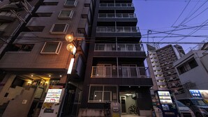 A multi-story building with balconies, a vending machine, and a bicycle parked outside. - BR KUJO - Self Check-In Only (Osaka)
