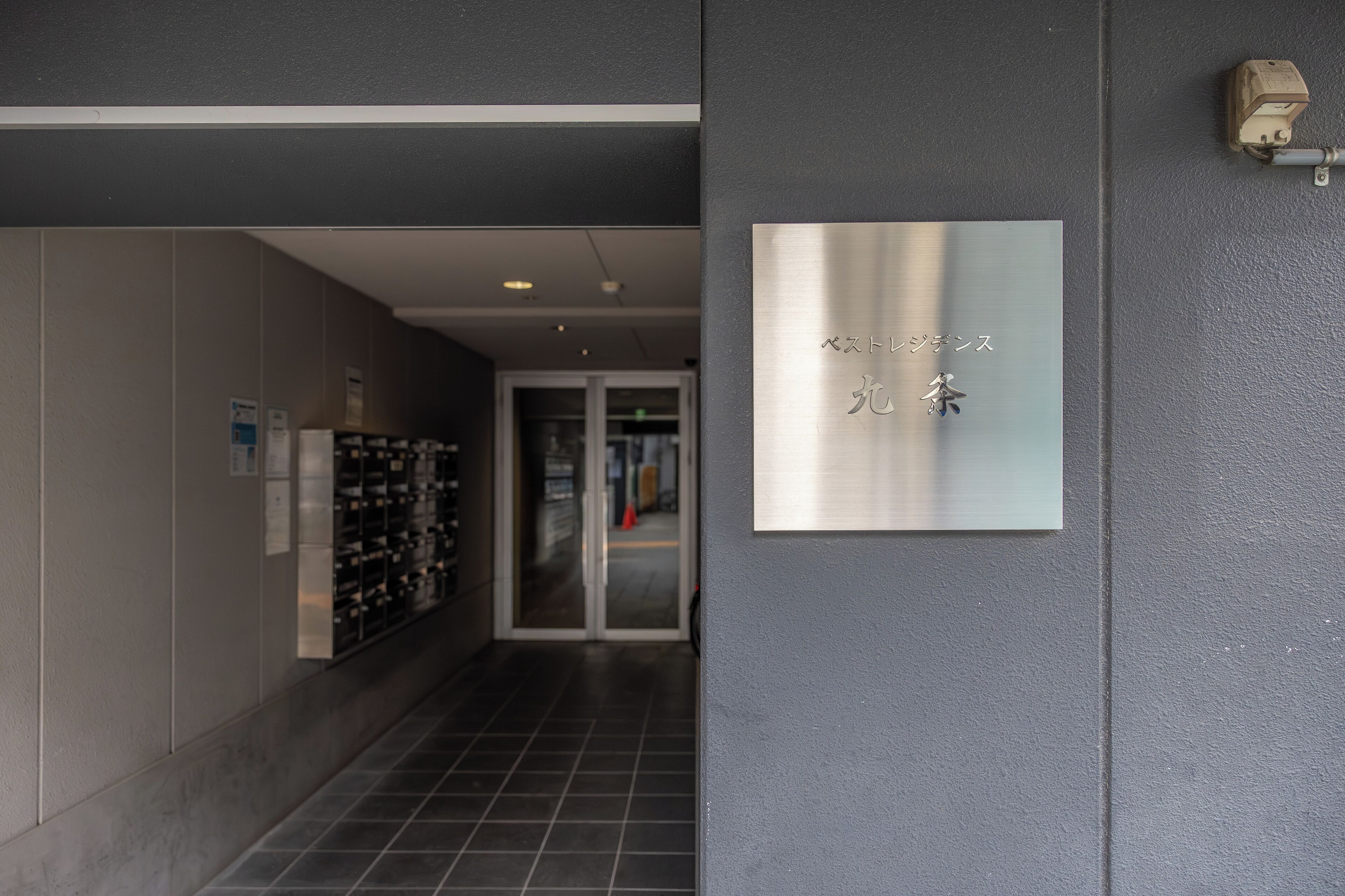 Un couloir avec un meuble à bouteilles de vin, une porte avec un panneau en verre et une enseigne avec du texte en japonais.