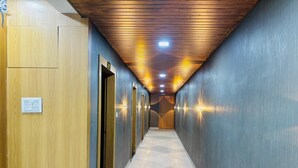 A hallway with wooden paneling on the left, a tiled floor, and recessed lighting. - HOTEL HUNTER  (Bardoli)