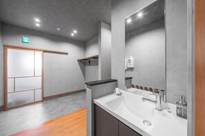 A modern bathroom with a large mirror, a sink, and a wooden floor. - E-US SAKAEDORI HOUSE (Sapporo)