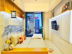 Une chambre d’hôtel moderne équipée d’un lit, d’une télévision, d’un bureau et offrant une vue sur le paysage urbain par la fenêtre.