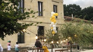 Eine Veranstaltung im Freien, im Hintergrund ein Gebäude, Lichterketten und Ballons.