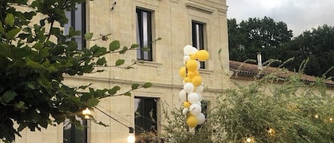 Eine Veranstaltung im Freien, im Hintergrund ein Gebäude, Lichterketten und Ballons.