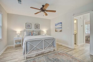 Ein Schlafzimmer mit Bett, Nachttischen, Deckenventilator und großem Fenster.
