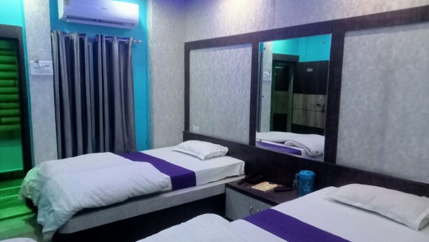 A hotel room with two beds, a mirror, an air conditioning unit, and a small table with a phone and a cup. - hotel Zinn satna (Satna)