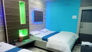 A hotel room with two beds, a nightstand, and a wall with a green-lit panel. - hotel Zinn satna (Satna)