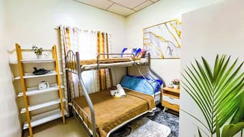 Habitación con literas, una mesita pequeña y una planta.