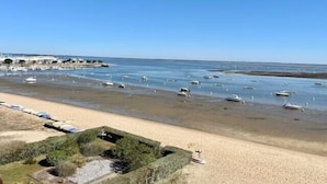 En strand med både i vandet og et sandområde med en lille have.
