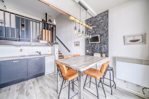 A modern kitchen with a wooden countertop, a dining table with chairs, a staircase, and a chalkboard wall with writing. - Beachfront apartment with direct beach access (Arcachon)