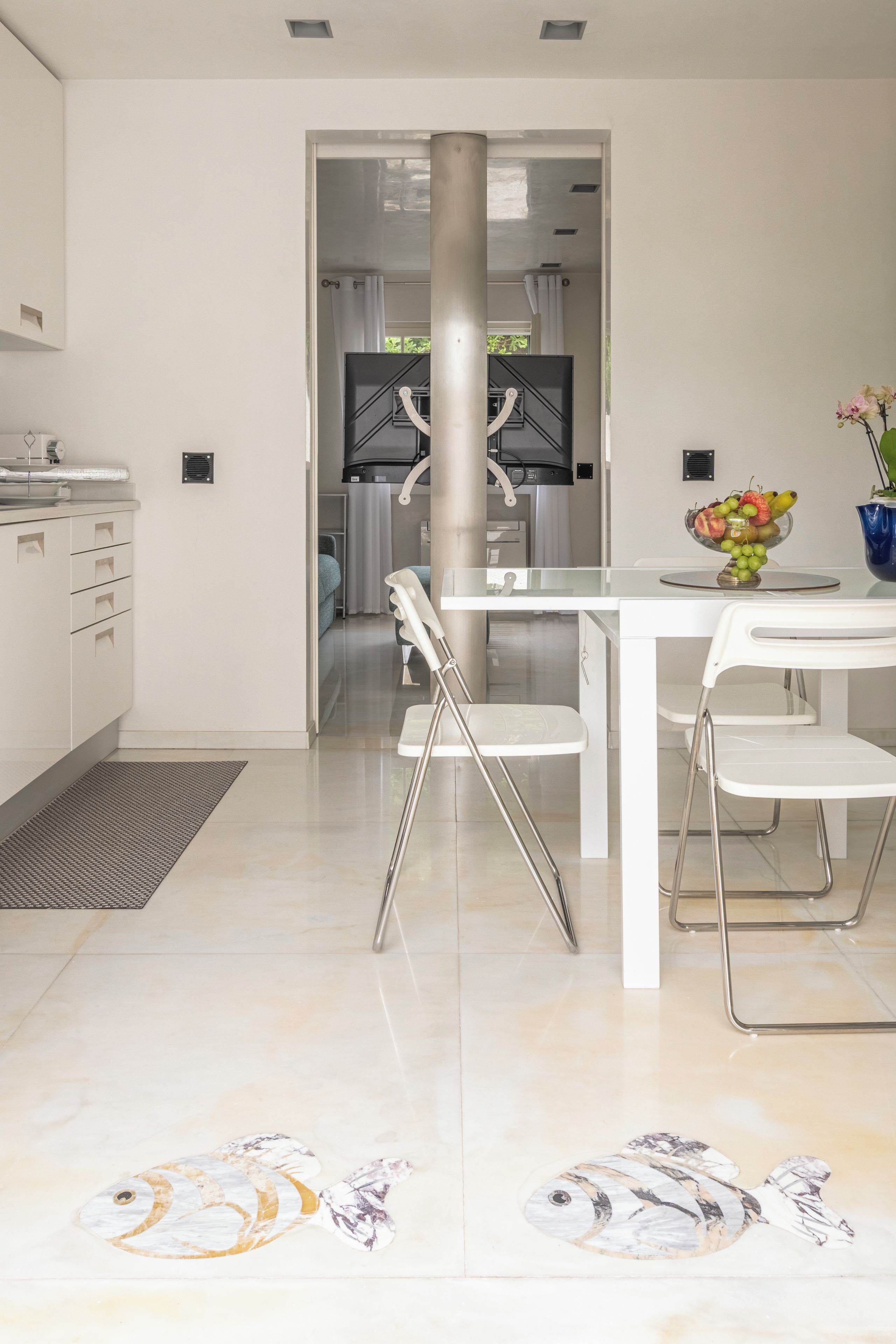 A modern kitchen with white cabinets, a stainless steel sink, and a dining area with a white table and chairs.