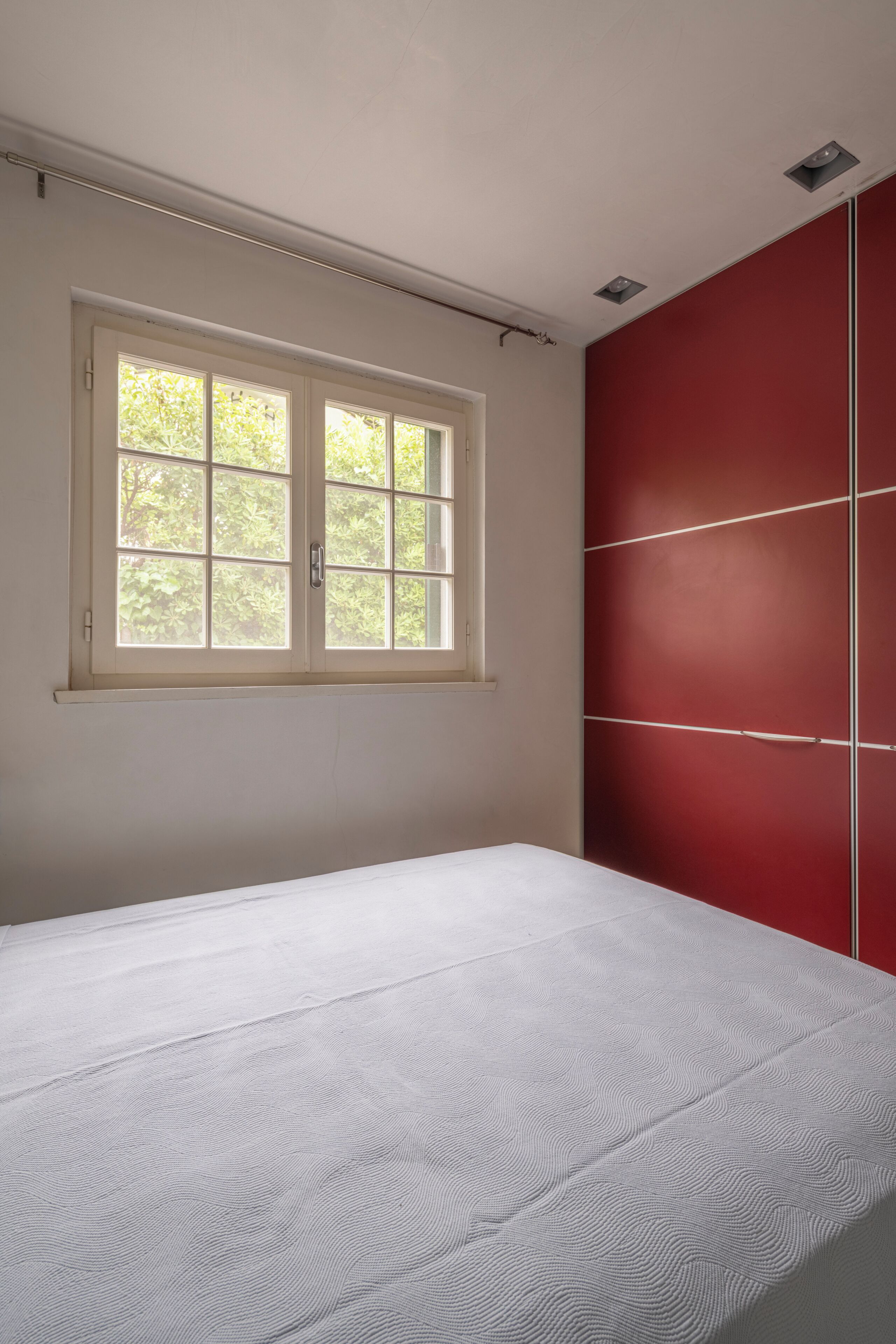 A room with a bed, a window, and a red wardrobe.