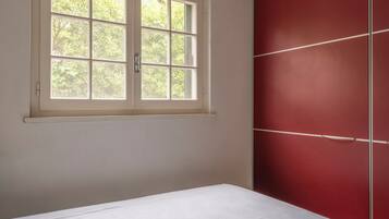 A room with a bed, a window, and a red wardrobe.