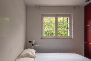 A bedroom with a bed, a window, and a nightstand with a lamp. - Bilocale Forte dei Marmi - Vivere Housing (Forte dei Marmi)