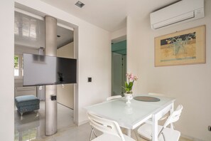 A modern kitchen with a flat-screen TV, a dining table with chairs, and a small stool. - Bilocale Forte dei Marmi - Vivere Housing (Forte dei Marmi)