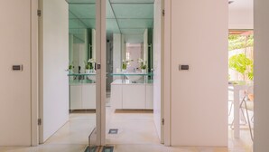 Een moderne keuken met glazen aanrechtbladen, witte kasten en uitzicht op het buitengebied.