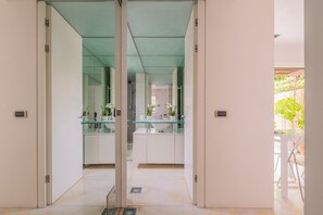 A modern kitchen with glass countertops, white cabinets, and a view of the outdoor area. - Two-room apartment in Forte dei Marmi Centro (Forte dei Marmi)