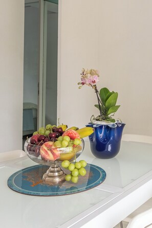 A fruit bowl with grapes, apples, and bananas on a table with a blue vase and an orchid. - Two-room apartment in Forte dei Marmi Centro (Forte dei Marmi)