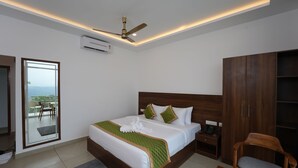 A modern bedroom with a large bed, a ceiling fan, an air conditioning unit, a wooden wardrobe, and a view of the outdoors through a sliding door. - Zeezmount Resorts & Spa Munnar (Devikolam)