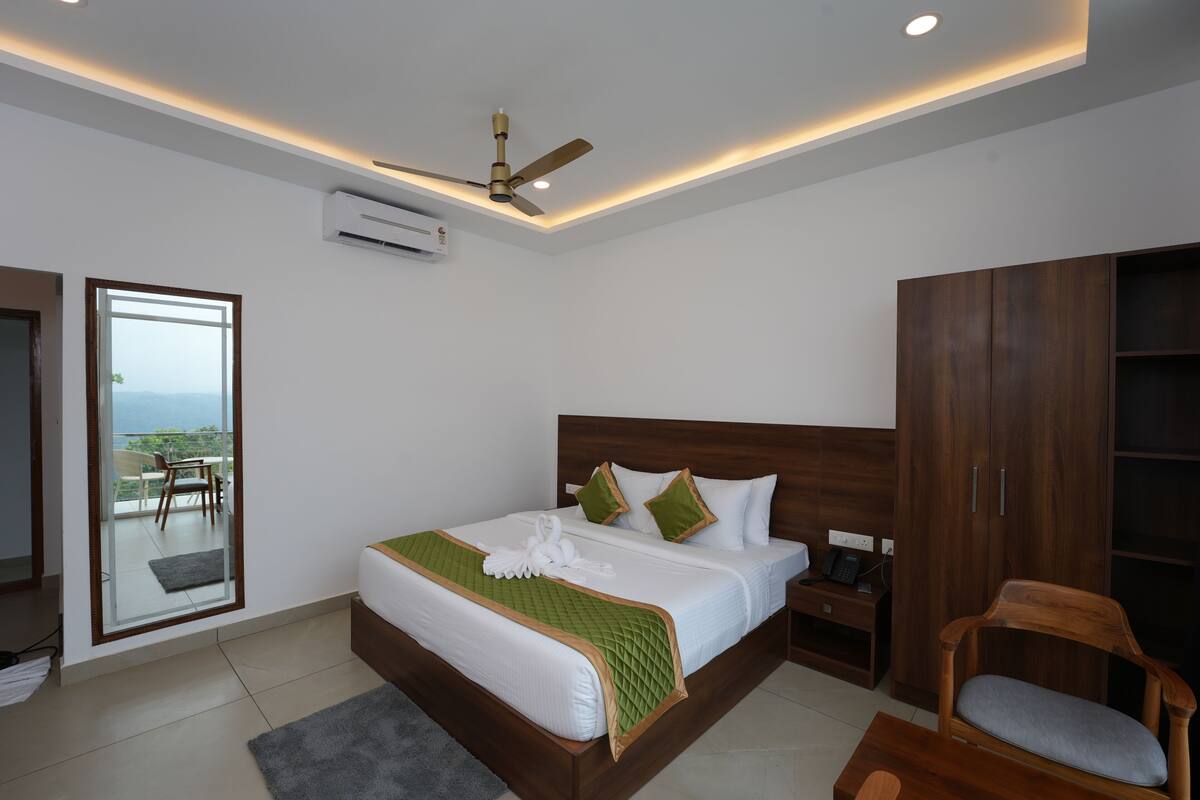 Un dormitorio moderno con una cama grande, ventilador de techo, aire acondicionado, armario de madera y vistas al exterior a través de una puerta corredera.