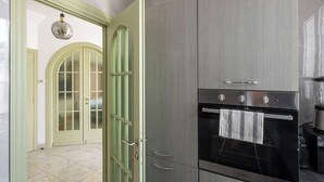 Una cocina con horno empotrado, lámpara colgante y puerta con marco verde.