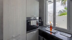 Una cocina moderna con gabinetes grises, horno integrado y cafetera.