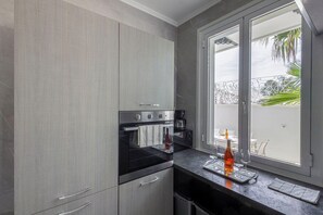 Une cuisine moderne avec des meubles gris, un four encastré et une machine à café.