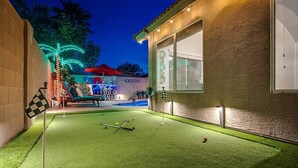 A well-lit backyard with artificial grass, a pool table, and a small pool. - Spacious 8-bedroom house in phenomenal Glendale with AC and gym (Glendale)